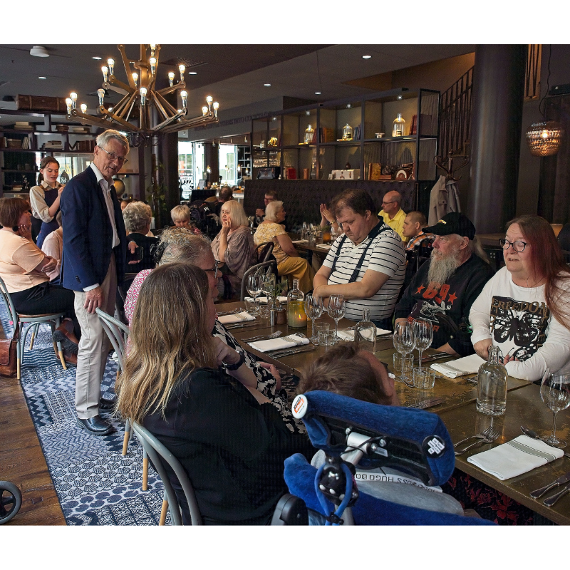 Bilden visar flera medlemmar och assistenter äter middag